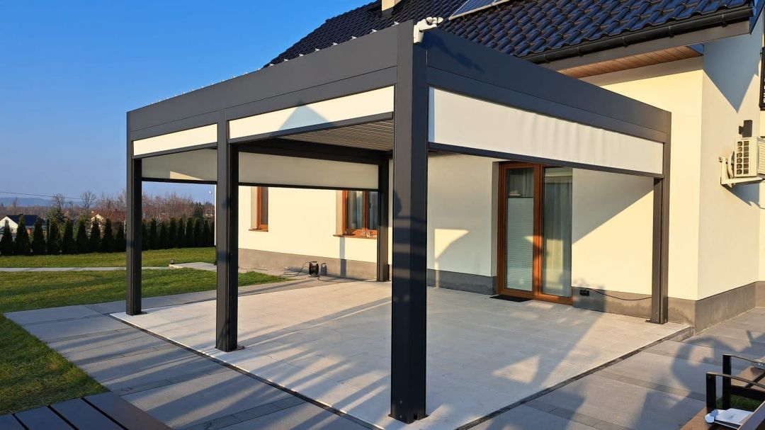 Pergolă bioclimatică antracit integrată în arhitectura casei, cu Screen-uri laterale pe două laturi ale terasei